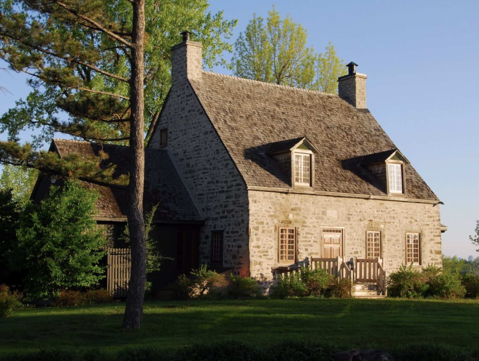 Maison ancestrale québécoise en pierre des champs, toit à deux versants et lucarnes